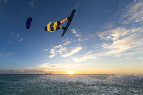 Duotone Boot wake-style kiteboard during wakestyle kitesurfing at an ocean beach at sunset