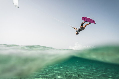 Duotone Boot wake-style kiteboard during kitesurfing in crystal-clear turquoise shallow water, Sicily