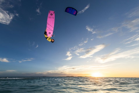 Duotone TS Freestyle SLS twin-tip kiteboard durante il kitesurf su una spiaggia al tramonto