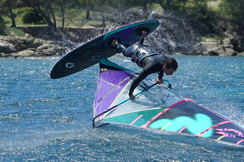 Duotone Idol LTD voile de freestyle lors de windsurf freestyle dans une baie côtière avec rivage boisé