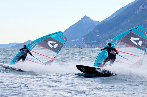 Duotone Warp_Fin race sail during windsurfing on a lake with mountain backdrop