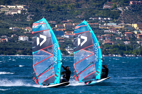 Duotone Warp_Fin race sail during windsurfing on a lake with mountainous backdrop