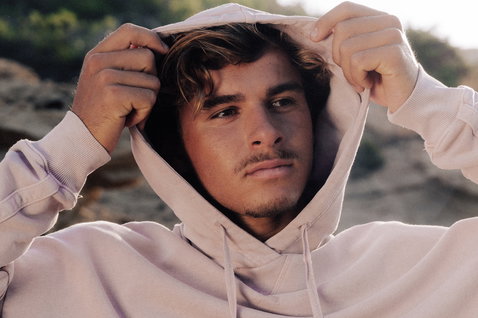 Duotone Hoody True Fade Out homme sweat à capuche en pose debout sur falaise côtière rocheuse