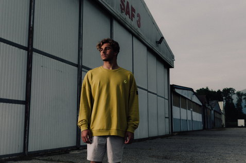Duotone Explore unisex shorts in light grey worn by a model in front of an industrial hangar