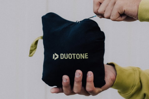 Chaqueta Duotone Explore Multishell guardada en su propia bolsa en azul marino oscuro con logo verde amarillo