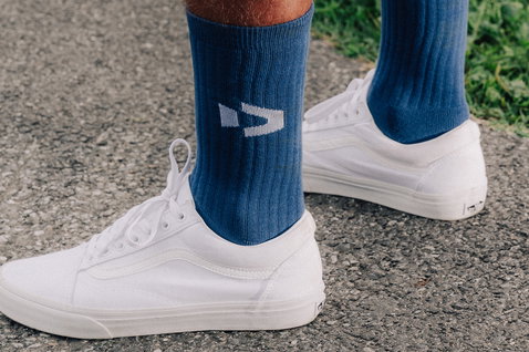 Chaussettes Duotone Originals en bleu acier avec logo blanc à la cheville, portées avec des sneakers blancs