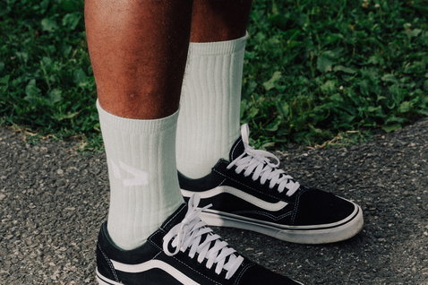 Chaussettes Duotone Originals en blanc cassé portées avec des baskets noires en extérieur