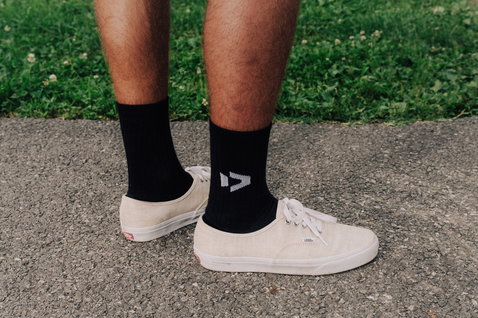 Chaussettes Duotone Originals en noir avec logo portées avec des baskets blanches en extérieur