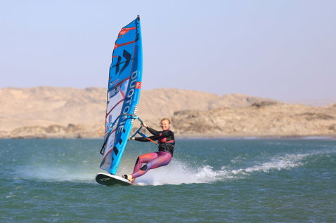 Duotone Falcon Speed D/LAB planche de windsurf lors de windsurf sur un lagon plat avec collines désertiques