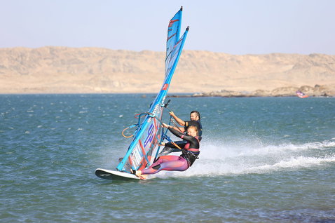 Duotone Falcon Speed D/LAB planche de windsurf lors de windsurf dans une baie côtière aux eaux calmes avec collines rocheuses