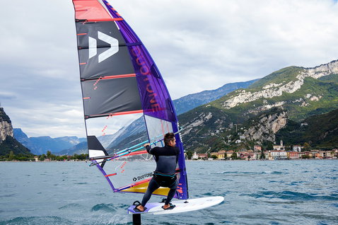 Duotone Warp Foil foil sail during foiling on an alpine lake with mountain backdrop and lakeside village