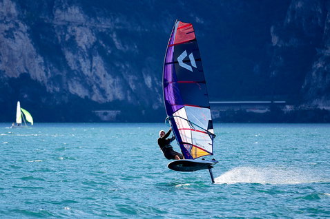 Duotone Falcon Foil D/LAB windsurf board during foiling on a mountain lake, likely Lake Garda, Italy
