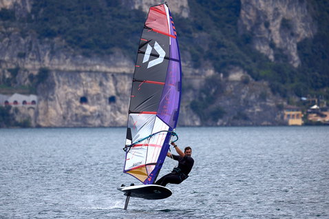 Duotone Falcon Foil D/LAB foil board during foiling on an alpine lake with rocky cliffs and village in background