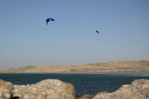 Kite LEI Duotone Evo SLS durante il kitesurf in laguna costiera arida con colline desertiche