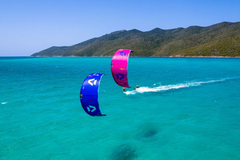 Duotone Evo SLS LEI kite durante il kitesurf in una baia tropicale con colline verdi sullo sfondo
