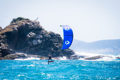 Duotone Evo SLS kite LEI durante il wing foiling su una costa oceanica con scogliere rocciose