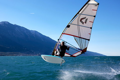 Duotone Blast windsurf board while windsurfing on an alpine lake with mountain backdrop