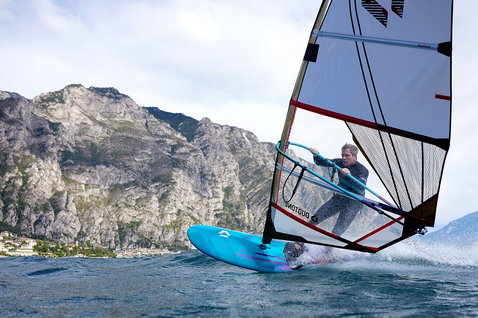 Duotone Blast windsurf board while windsurfing on a mountain lake in cyan blue