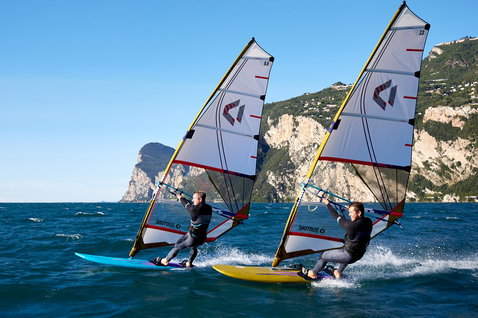 Duotone Blast SLS windsurf board during windsurfing on an alpine lake with mountain cliffs in the background