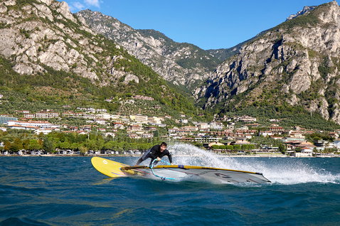 Duotone Blast SLS windsurf board during windsurfing on an alpine lake with mountain backdrop and lakeside town