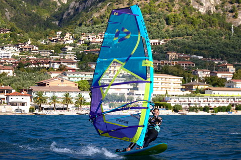 Duotone E_Pace freeride sail 6.6m² during windsurfing on a lake with mountain backdrop