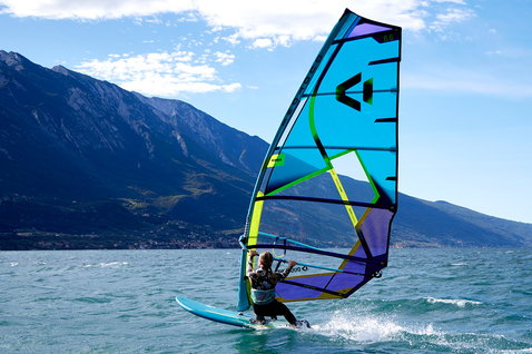 Duotone E_Pace freeride sail during windsurfing on an alpine lake with mountain backdrop