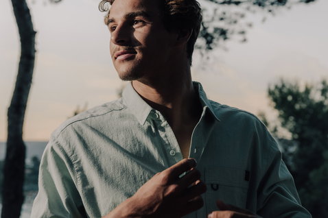 Chemise manches courtes Duotone Apparel Shirt SS True unisex en pose debout sur une colline côtière méditerranéenne avec arbres et mer