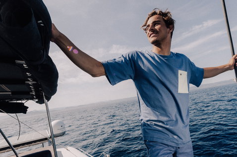 T-Shirt beim Stehen auf dem Bootsdeck am Meer in hellblau und weiß