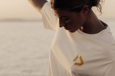 Duotone Apparel Tee SS CB women's short sleeve t-shirt worn standing at the ocean beach in natural off-white