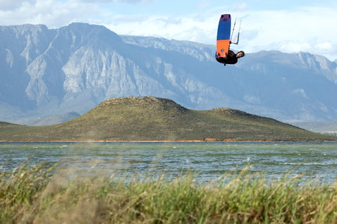 Duotone Gonzales twin-tip kiteboard lors du kitesurf sur un lac intérieur avec montagne en arrière-plan
