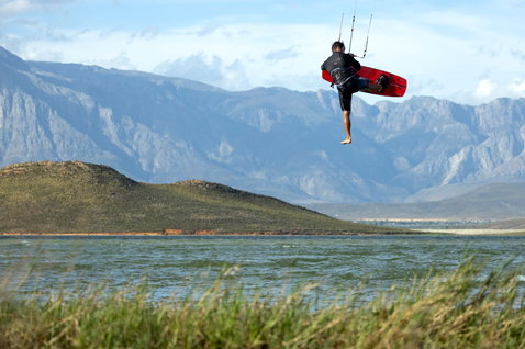 Duotone Gonzales twin-tip kiteboard en kitesurf sur un lac intérieur avec massif montagneux et broussailles