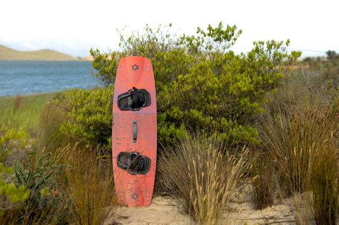 Duotone Gonzales twin-tip kiteboard en train de faire du kitesurf sur une plage côtière avec lagon en arrière-plan