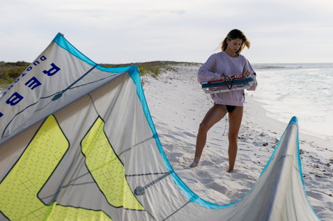 Duotone Apparel Sweater True Fade Out mujer durante la preparación para el kitesurf en playa con dunas de arena blanca