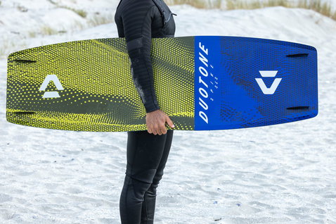 Duotone Spike SLS twin-tip kiteboard during kitesurfing on a sandy beach with dunes