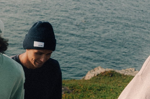 Bonnet Duotone New Era Logo bleu marine foncé porté sur une falaise côtière avec vue sur l'océan
