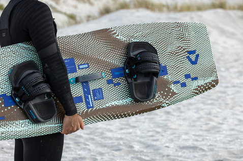 Duotone Spike Concept Blue twin-tip kiteboard during kitesurfing at a sandy beach with white sand dunes