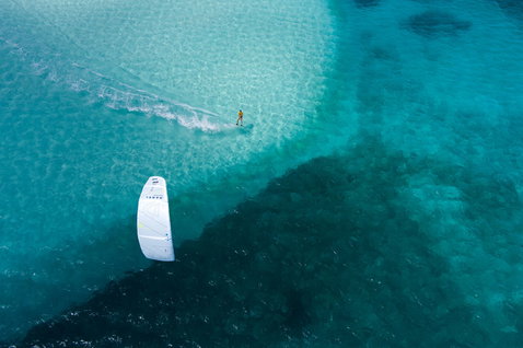 Duotone Spike twin-tip kiteboard during kitesurfing in a shallow tropical ocean with coral reef