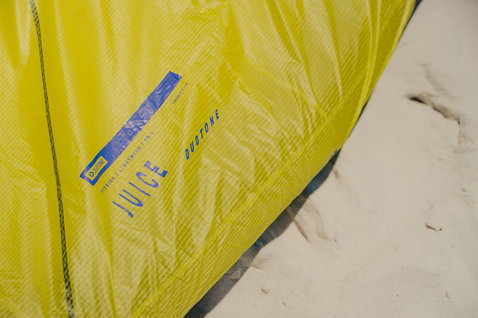 Duotone Juice LEI Kite in gelbgrün, blau und weiß am Strand