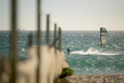 Duotone D/LAB LEI kite lors du kitesurf en mer avec littoral rocheux au premier plan