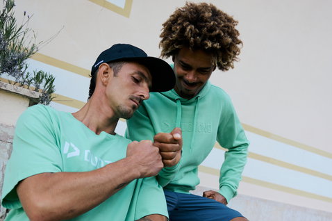 Sweat à capuche unisexe Duotone Originals en vert menthe porté par deux modèles en extérieur