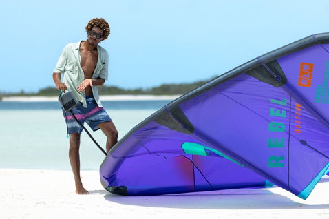 Duotone Lazepump elektrische Luftpumpe beim Kitesurfen-Vorbereiten an einem tropischen Strand mit türkisblauem Wasser