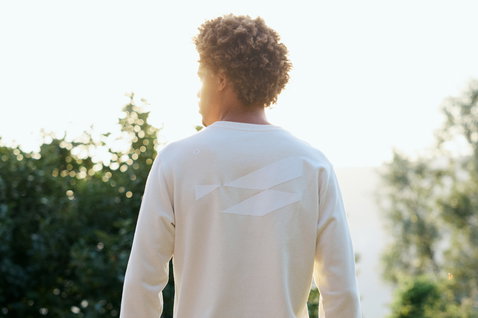 Duotone Concept Blue sweater in natural off-white with back graphic print, worn by a man outdoors