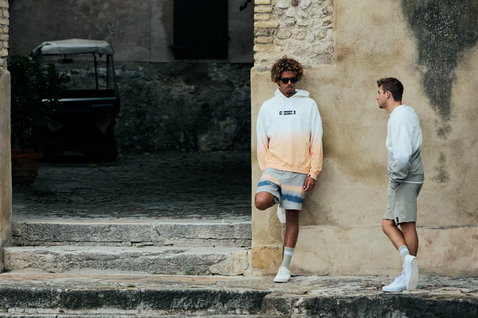 Sweat à capuche Duotone Apparel True homme avec dégradé dip-dye blanc et pêche lors d'une séance lifestyle en cadre méditerranéen