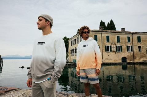 Sweat à capuche Duotone True homme en dégradé dip-dye pêche et blanc porté au bord d'un lac