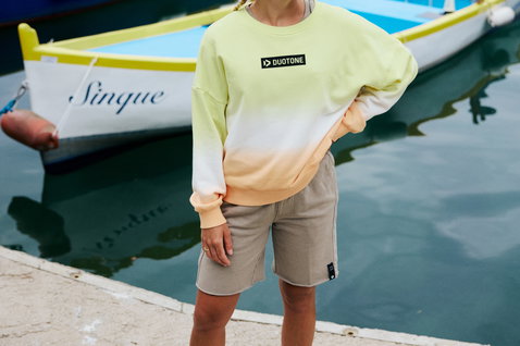 Short sweat Duotone Apparel True en taupe poussiéreux porté dans un port en été
