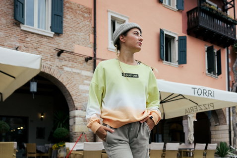 Sweat femme Duotone True coloris honey melon dip-dye porté lors d'une promenade sur une place italienne