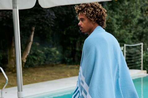 Serviette Duotone Towel Logo en bleu clair portée au bord de la piscine en été