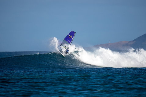 Duotone Super Hero D/LAB wave sail during wave riding on the open ocean with coastal headland in the background