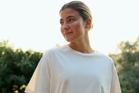 Duotone Concept Blue T-shirt in natural ecru organic cotton worn by a woman outdoors at golden hour