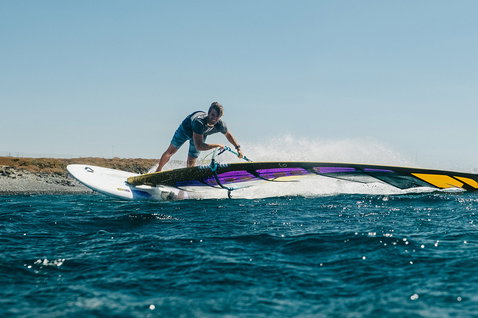 Duotone Falcon Fin D/LAB planche de windsurf lors de windsurf sur océan ouvert près d'une côte rocheuse